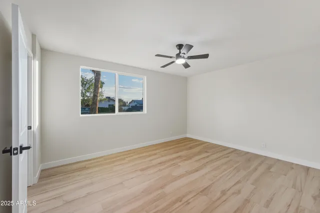 a view of empty room with wooden floor and fan