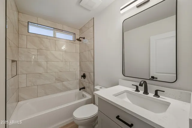 a bathroom with a bathtub shower sink vanity mirror and toilet