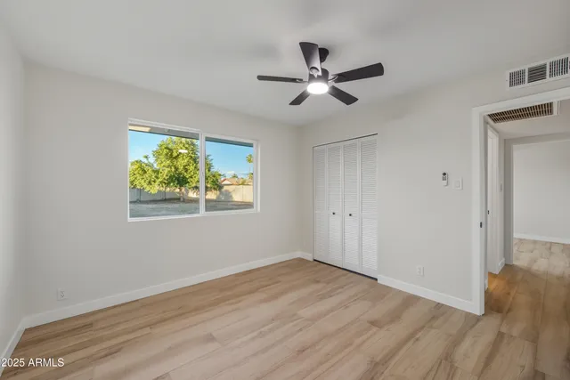 a view of empty room with wooden floor and fan