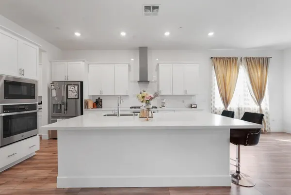 a large white kitchen with stainless steel appliances