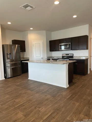 a large kitchen with stainless steel appliances granite countertop a stove top oven a refrigerator and a sink