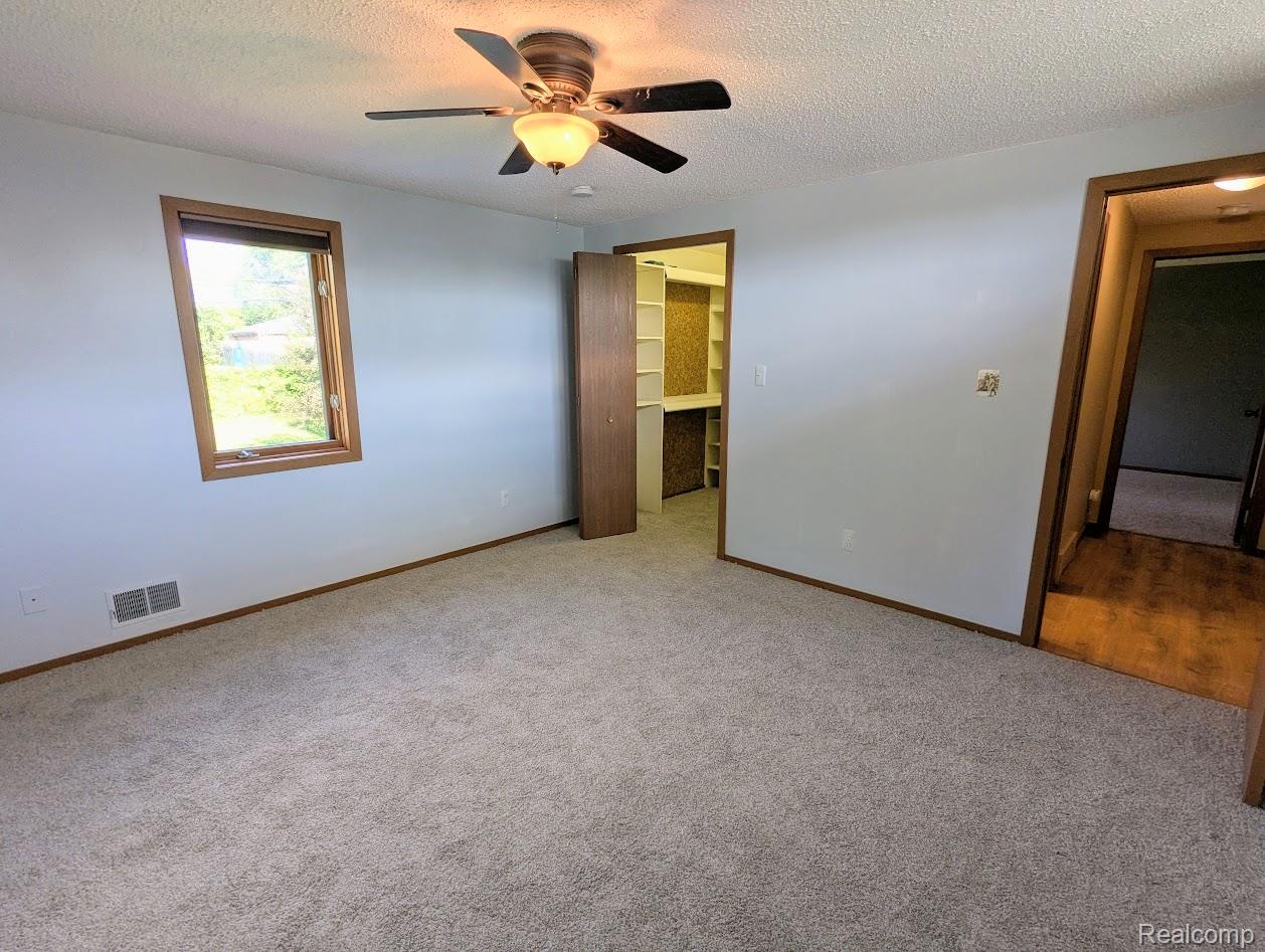2316 Crescent Lake Road Waterford, MI 48329 - Photo 6 of 17 Spacious room featuring carpeting, a ceiling fan with light fixture, and a window with wood trim