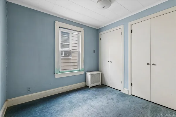 a view of an empty room with a window and closet area