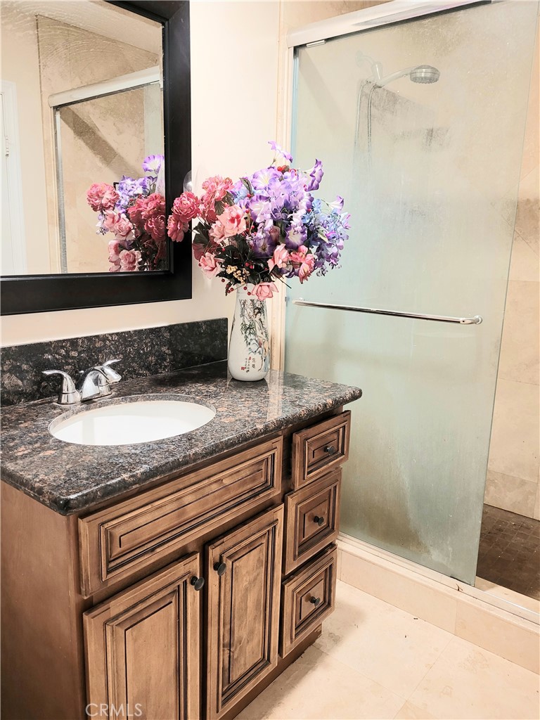 11896 Firebrand Circle Garden Grove, CA 92840 - Photo 21 of 37 a bathroom with a granite countertop sink a mirror and a shower