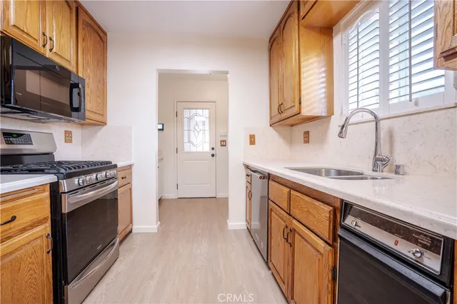 a kitchen with stainless steel appliances granite countertop a sink a stove and a microwave oven with cabinets