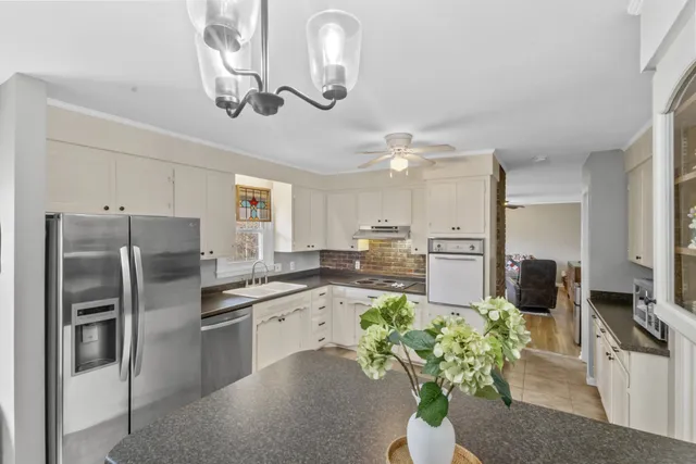 a kitchen with stainless steel appliances granite countertop a refrigerator a sink dishwasher a stove with white cabinets