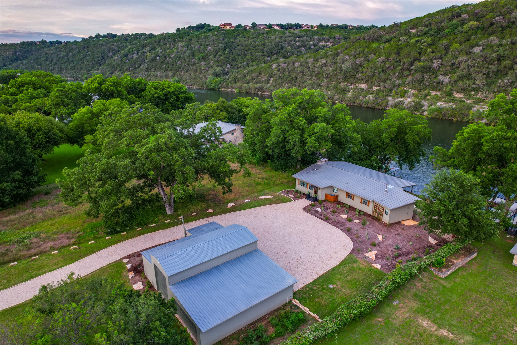 303 Lago Verde Road Austin, TX 78734 - Photo 37 of 39 Perched above the water, this serene property boasts a gravel driveway leading to a private residence and detached structure.