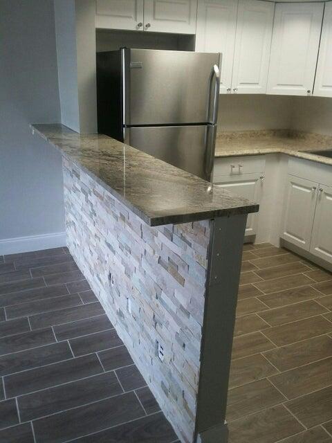 660 Glouchester Street, Unit 105 Boca Raton, FL 33487 - Photo 5 of 13 a kitchen with kitchen island a sink dishwasher a refrigerator and wooden cabinets