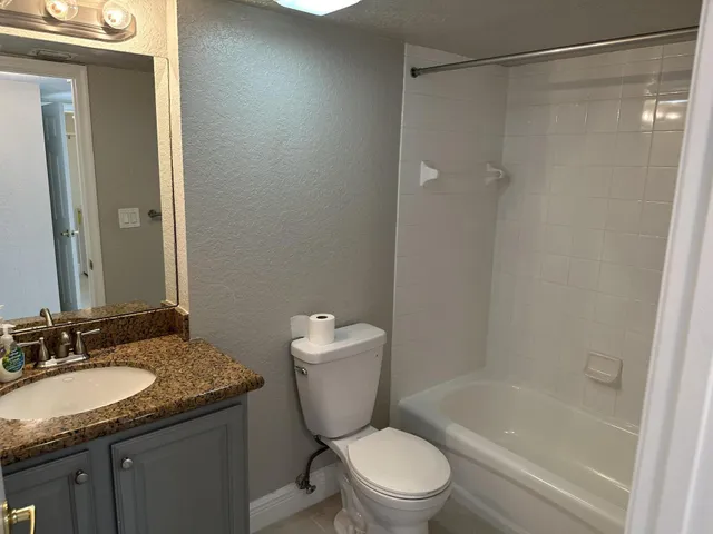 a bathroom with a granite countertop sink toilet and shower