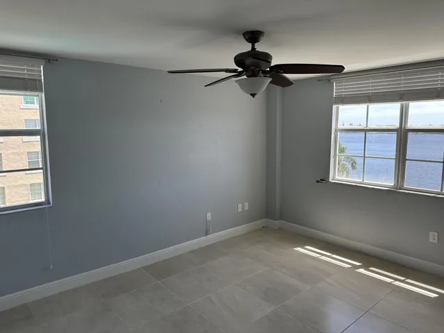 an empty room with windows and fan
