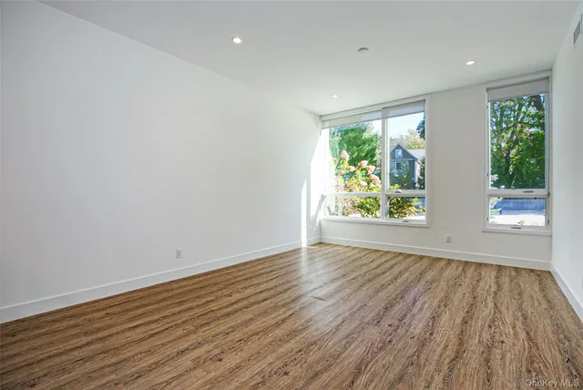 a view of an empty room with wooden floor and window