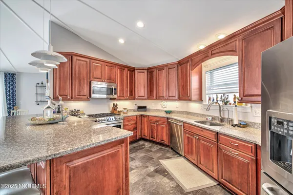 a kitchen with stainless steel appliances granite countertop wooden cabinets a sink and dishwasher a stove top oven with wooden floor