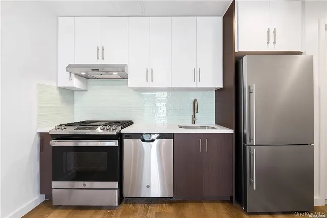 a kitchen with stainless steel appliances granite countertop a refrigerator a stove a sink and white cabinets