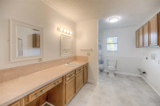 a spacious bathroom with a granite countertop sink a toilet and a mirror