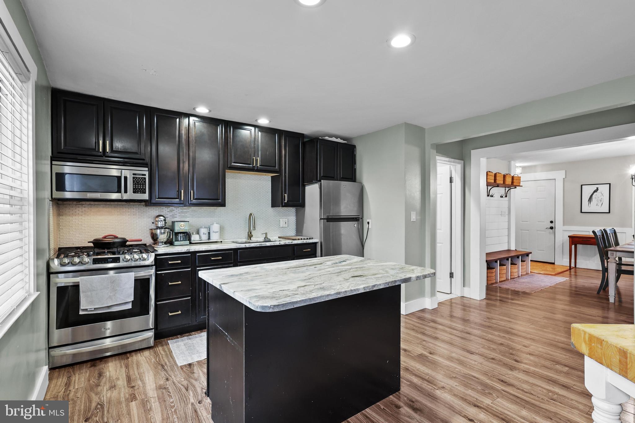 1020 Dartmouth Road Baltimore, MD 21212 - Photo 15 of 46 a kitchen with stainless steel appliances granite countertop a stove top oven a sink dishwasher a refrigerator and a dining table with wooden floor
