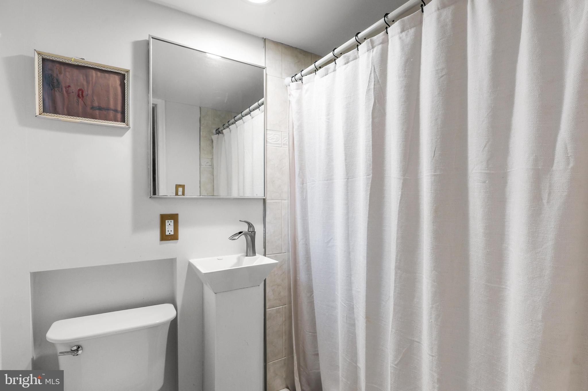 1020 Dartmouth Road Baltimore, MD 21212 - Photo 38 of 46 a bathroom with a sink a toilet and shower curtain