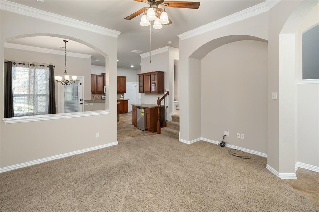 4245 Swan Forest Drive, Unit B Carrollton, TX 75010 - Photo 6 of 26 Unfurnished living room with ceiling fan, light carpet, a chandelier, arched walkways, and crown molding