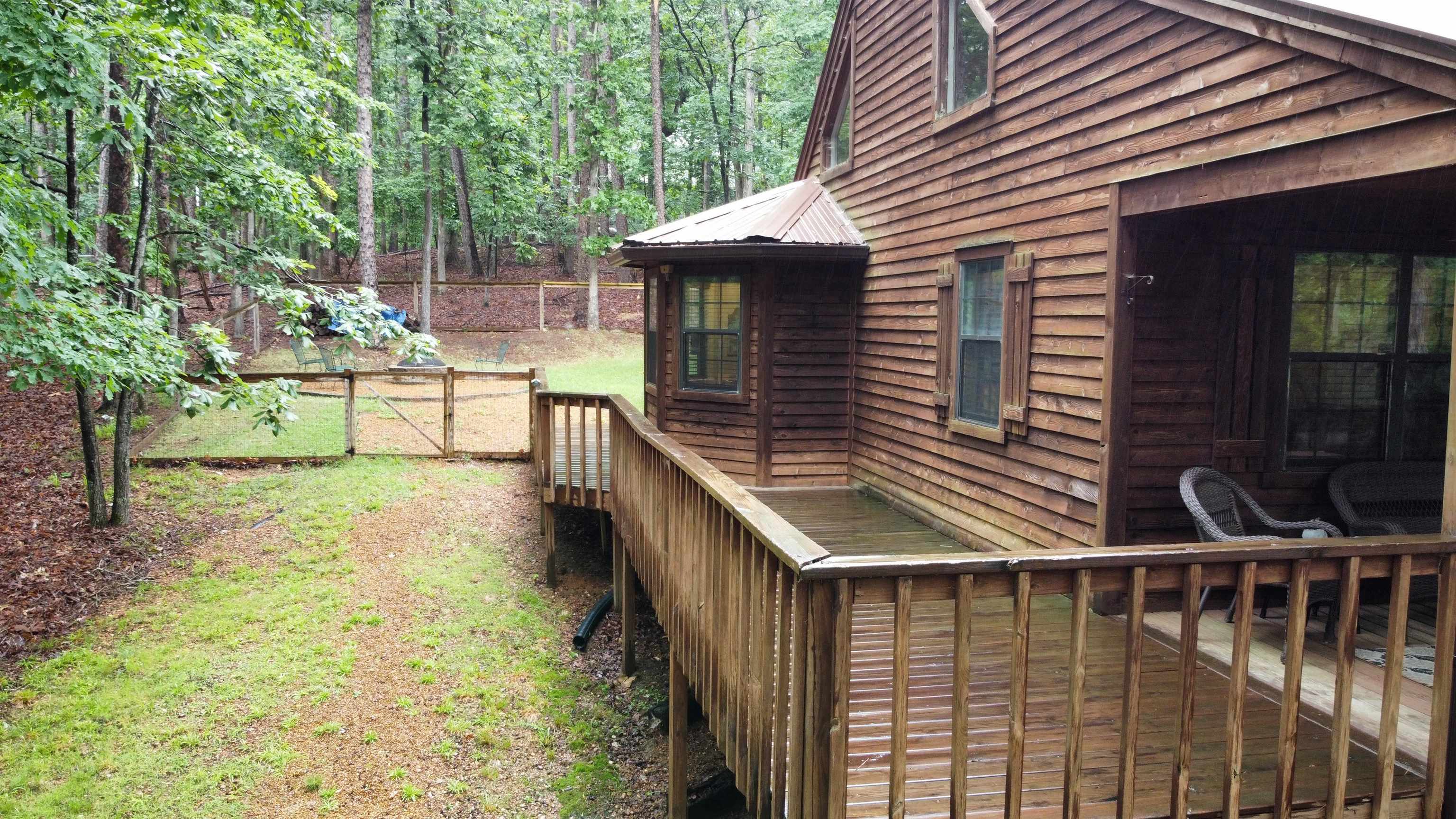 275 Bryson Harbor Road Counce, TN 38326 - Photo 3 of 23 Wood-sided exterior featuring a prominent deck railing, bay window with a corrugated metal roof, and an expansive wooded backdrop