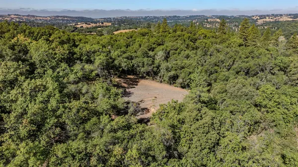 an aerial view of a houses with a yard and mountain view