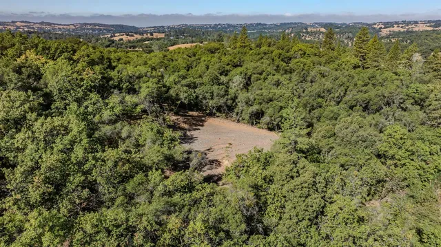 an aerial view of a houses with a yard and mountain view