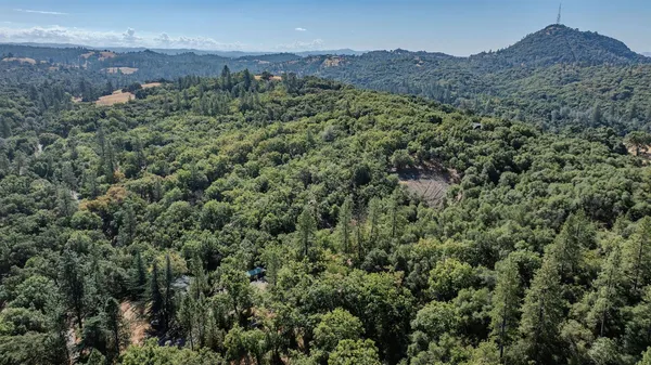 an aerial view of a houses with a lush green hillside