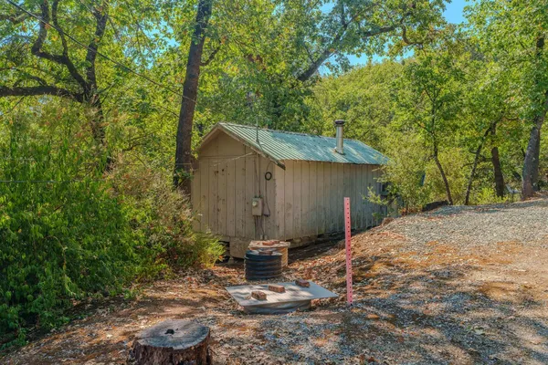 a view of a barn in the backyard with large trees