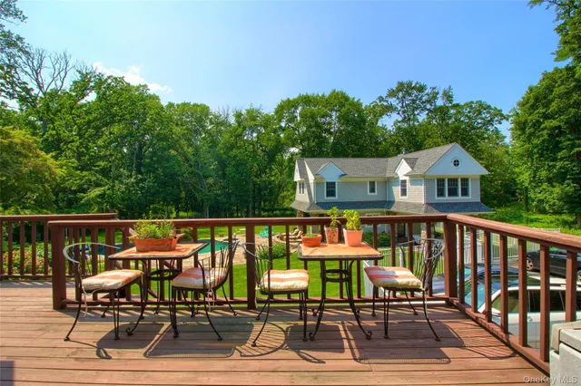 a roof deck with table and chairs a barbeque with potted plants and large trees
