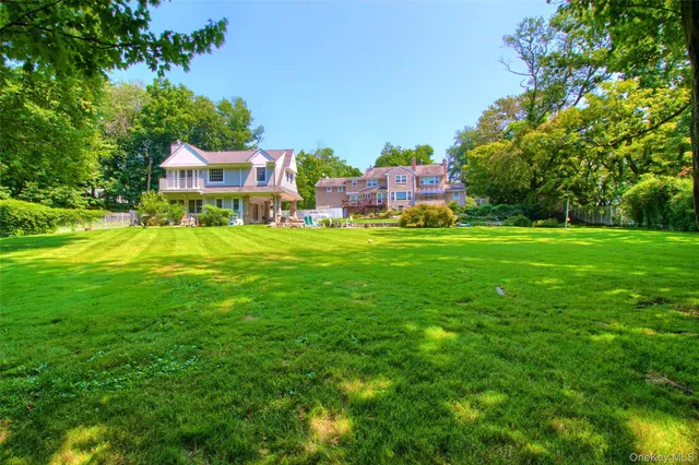 a backyard of a house with table and chairs plants and large tree