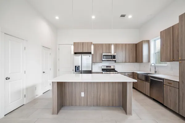 a large kitchen with stainless steel appliances a refrigerator a stove top oven a sink and dishwasher