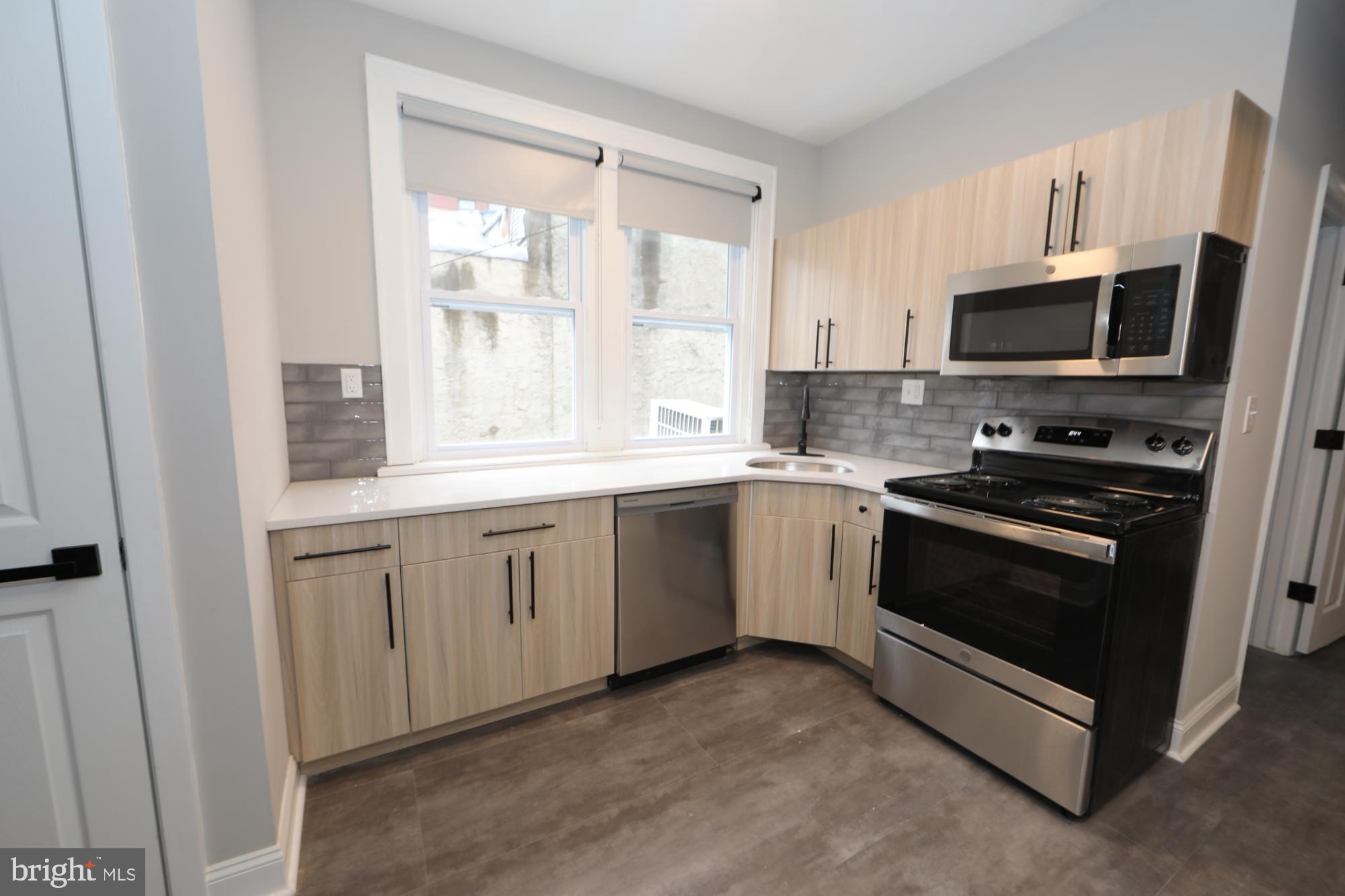 931 Spring Garden Street, Unit 2 Philadelphia, PA 19123 - Photo 17 of 24 a kitchen with stainless steel appliances granite countertop a stove a sink and a microwave