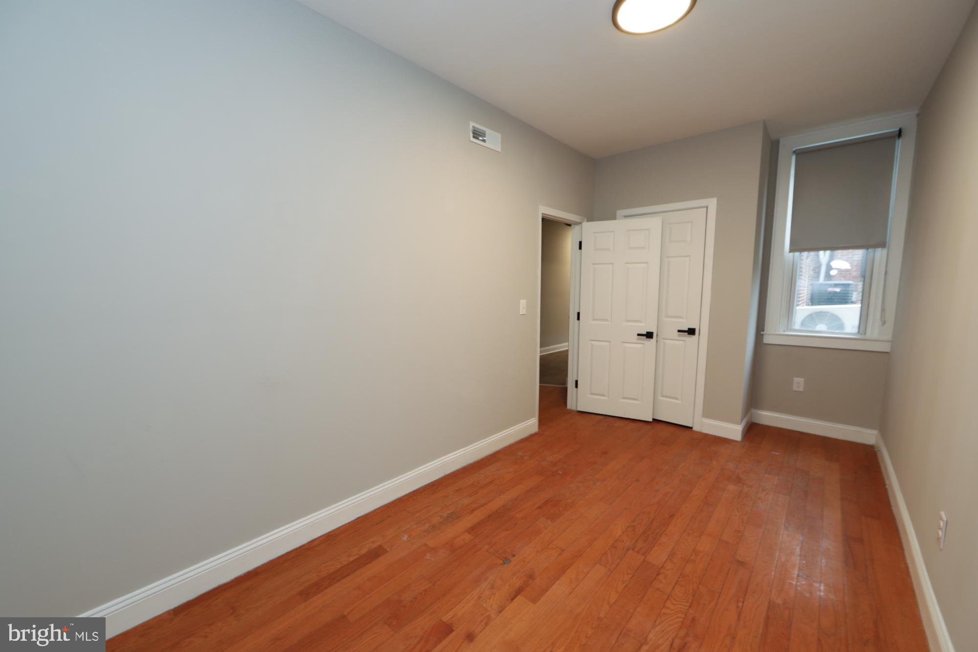 931 Spring Garden Street, Unit 2 Philadelphia, PA 19123 - Photo 4 of 24 a view of an empty room with wooden floor and a window
