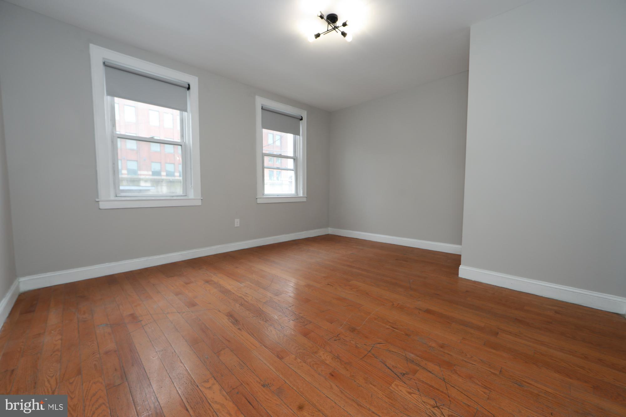 931 Spring Garden Street, Unit 2 Philadelphia, PA 19123 - Photo 6 of 24 an empty room with wooden floor and windows
