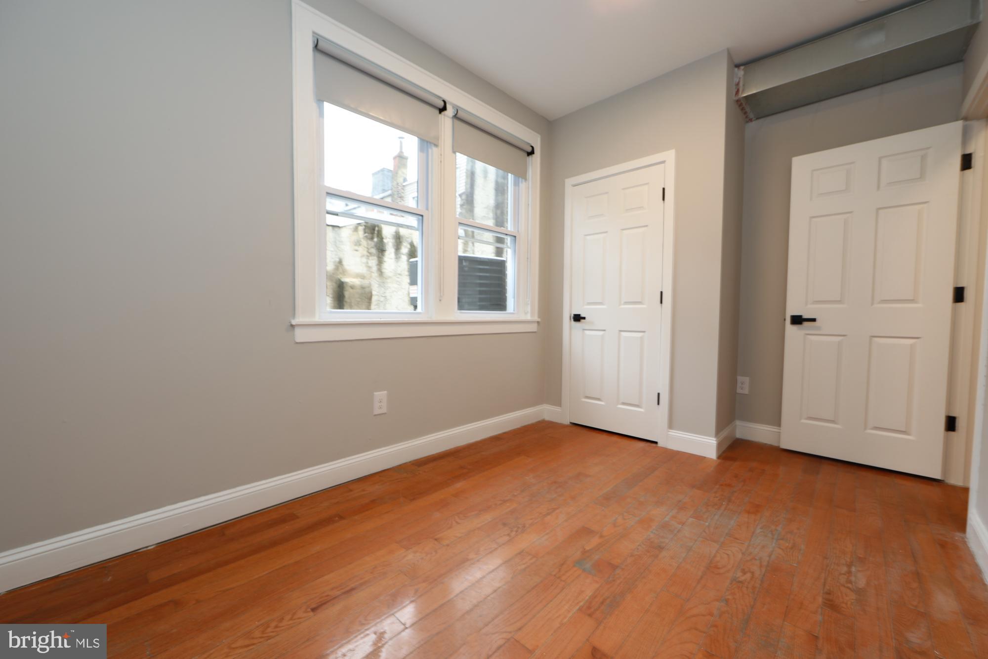 931 Spring Garden Street, Unit 2 Philadelphia, PA 19123 - Photo 9 of 24 an empty room with wooden floor and windows