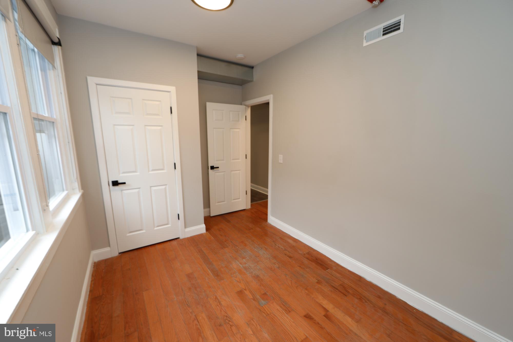 931 Spring Garden Street, Unit 2 Philadelphia, PA 19123 - Photo 10 of 24 an empty room with wooden floor and windows