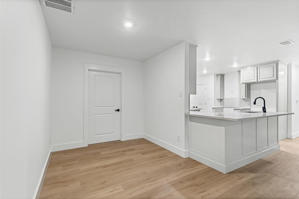 1509 Shirley Way Bedford, TX 76022 - Photo 7 of 26 Kitchen with a peninsula, light wood-style floors, light stone countertops, white cabinetry, and recessed lighting