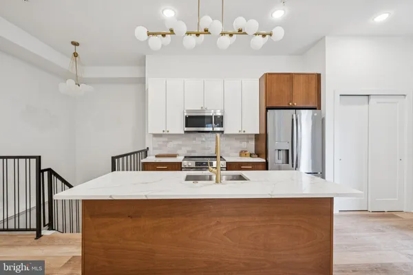 a kitchen with kitchen island granite countertop a sink a counter top space cabinets and stainless steel appliances