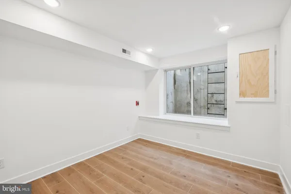 a view of an empty room with wooden floor and a window