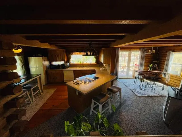 a view of a dining room with furniture a kitchen and chandelier