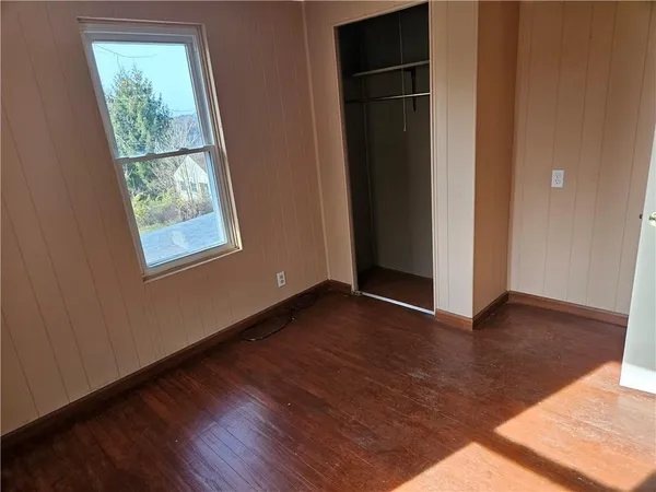 an empty room with wooden floor cabinet and windows