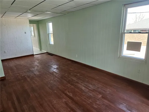 an empty room with wooden floor and windows