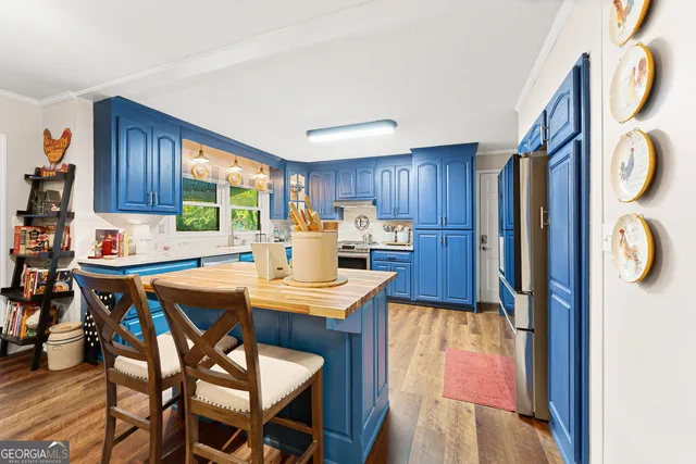 a kitchen with stainless steel appliances kitchen island granite countertop a table chairs sink and cabinets