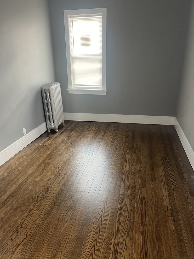1825 East 79th Street, Unit 2R Chicago, IL 60649 - Photo 5 of 8 an empty room with wooden floor and windows
