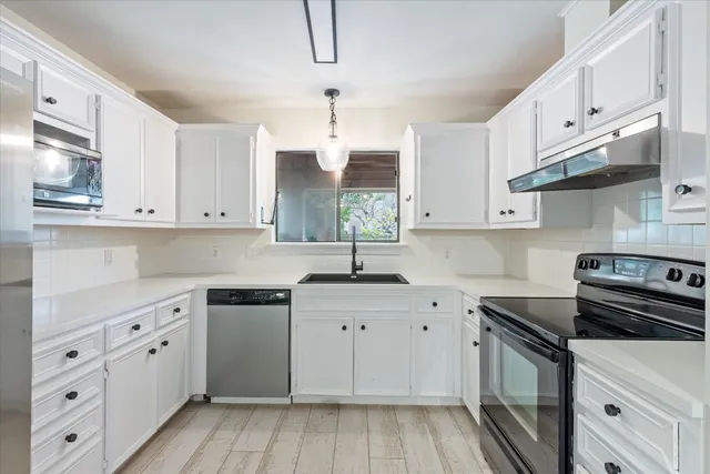 a kitchen with cabinets appliances a sink and a counter top space