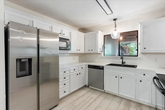 a kitchen with granite countertop a refrigerator sink and cabinets