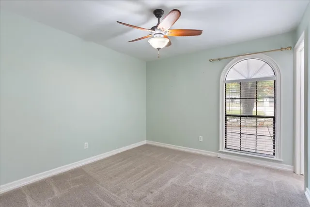 an empty room with windows and ceiling fan