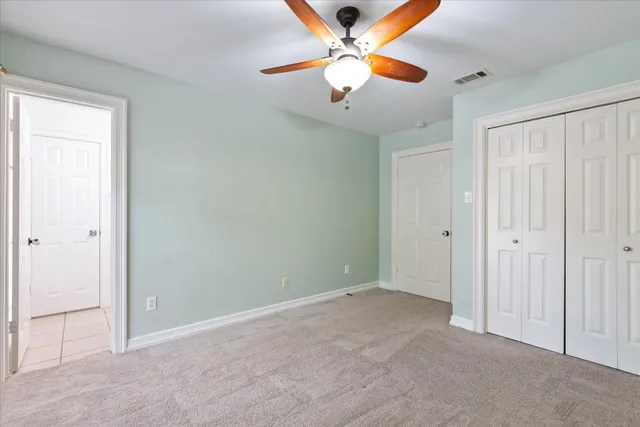 an empty room with closet and a chandelier fan