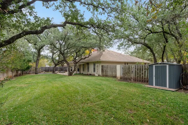 a view of a yard in front of a house with large trees
