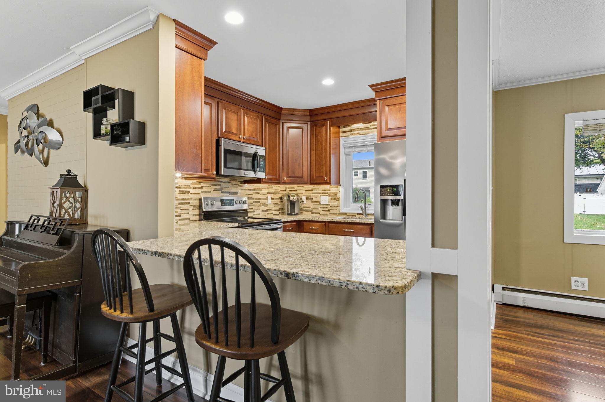 9 Newberry Lane Levittown, PA 19054 - Photo 8 of 36 a kitchen with stainless steel appliances granite countertop a stove top oven a sink a dining table and chairs with wooden floor