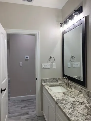 a bathroom with a granite countertop sink and a mirror