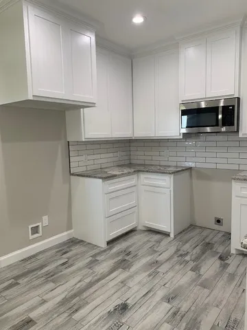 a kitchen with stainless steel appliances granite countertop a stove a sink and white cabinets